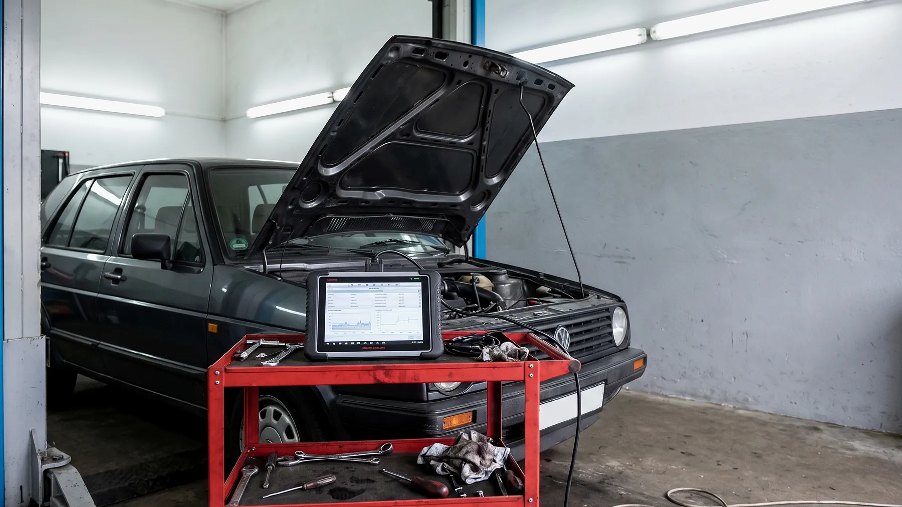 Diagnose am Fahrzeug - HZ Performance Diagnosetablet auf einem Werkzeugwagen, angeschlossen an ein Fahrzeug mit geöffneter Motorhaube