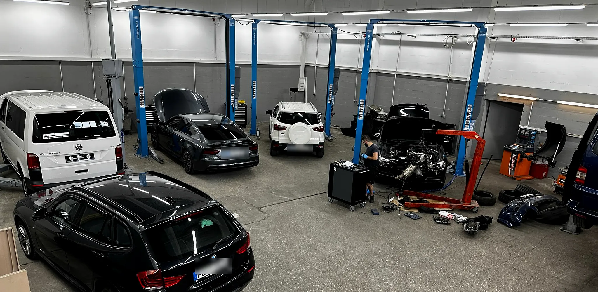 Werkstatthalle von HZ Performance in Zirndorf mit Hebebühnen; im Hintergrund arbeitet ein Mechaniker an einem ausgebauten Motor